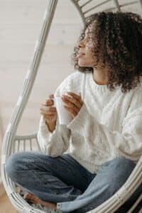 An African American woman holding a cup of coffee, reflecting calm, presence, and a moment of quiet awareness.