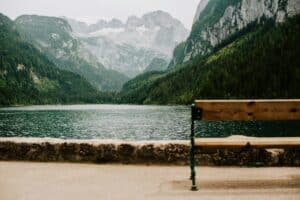 A scenic view of a lake and mountains with a bench, symbolizing reflection, clarity, and emotional grounding.