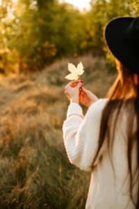 A woman holding a leaf in a natural setting, symbolizing connection, presence, and gentle mind-body awareness.