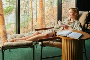 A woman sitting in a chair reading with coffee, symbolizing mindfulness, comfort, and a moment of personal calm.