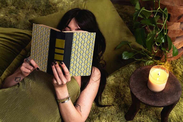 woman reading a book next to a lit candle