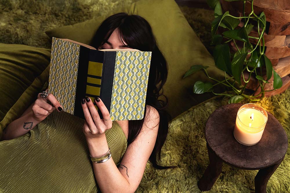 woman reading a book next to a lit candle