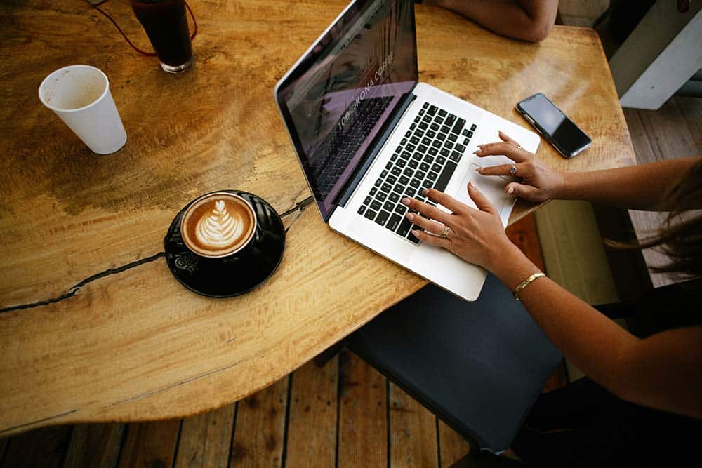 Person using a MacBook Pro on a brown wooden table