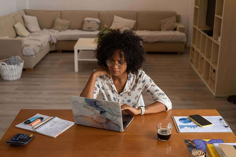 Woman sitting at a table using a laptop for work.