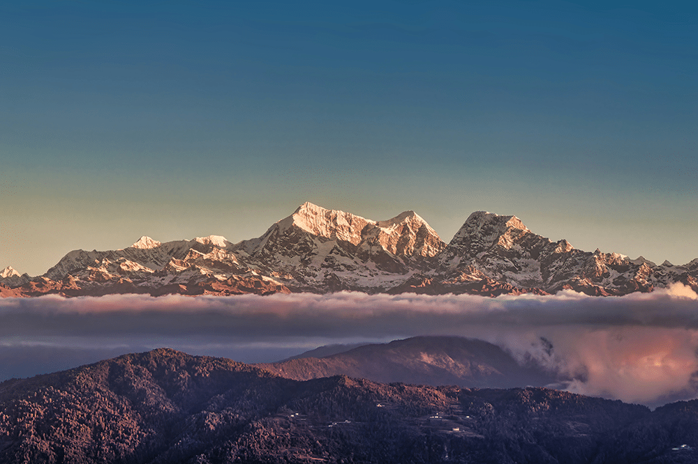 snow capped mountains rise above clouds at sunrise